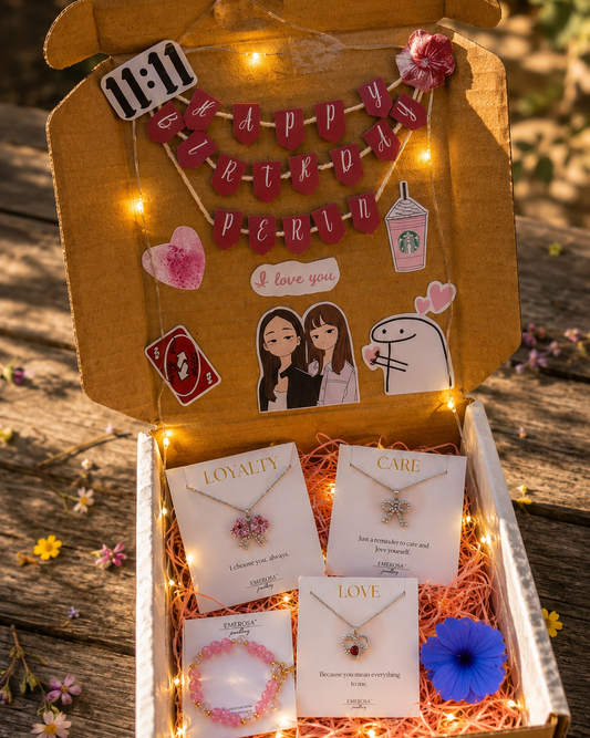 Gift box with necklaces, cards, and decorative items on a wooden surface