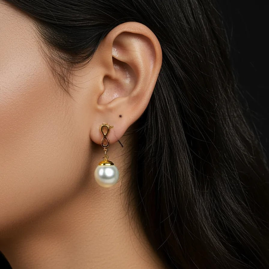 Close-up of an ear wearing a pearl earring with a dark background