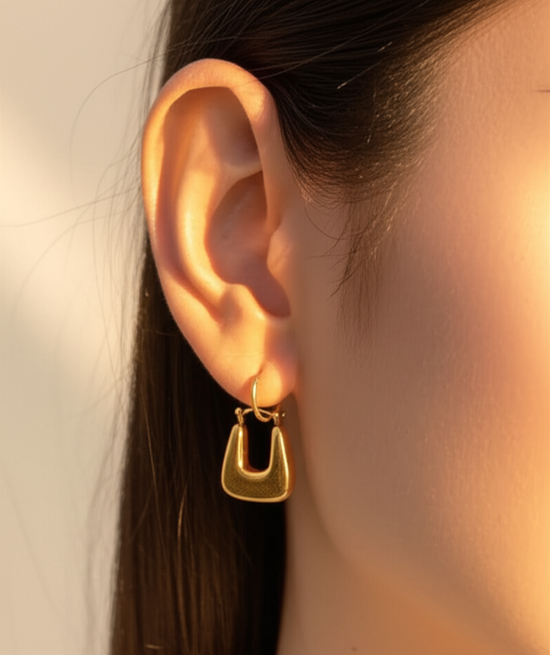 Gold hoop earring worn by a person with a neutral background