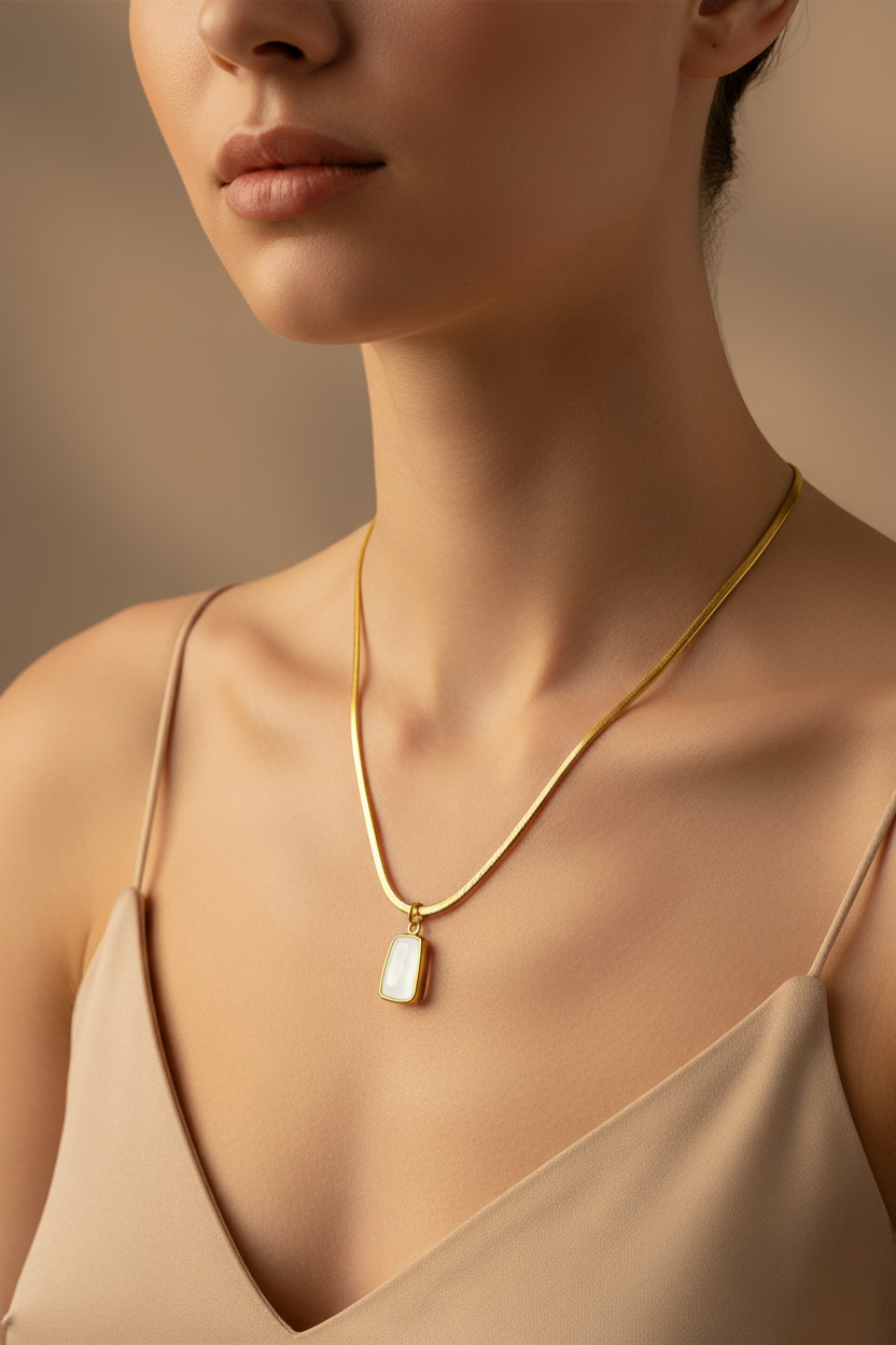 Close-up of a woman wearing a gold necklace with a pendant against a neutral background
