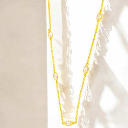 Gold necklace with embedded stones on a neutral background