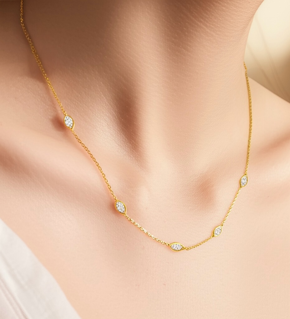 Gold necklace with small diamonds on a person wearing a white top.