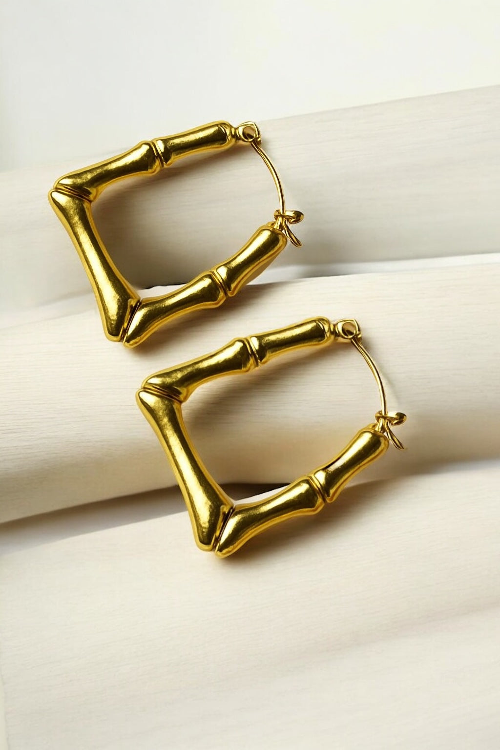 Gold hoop earrings on a light beige surface